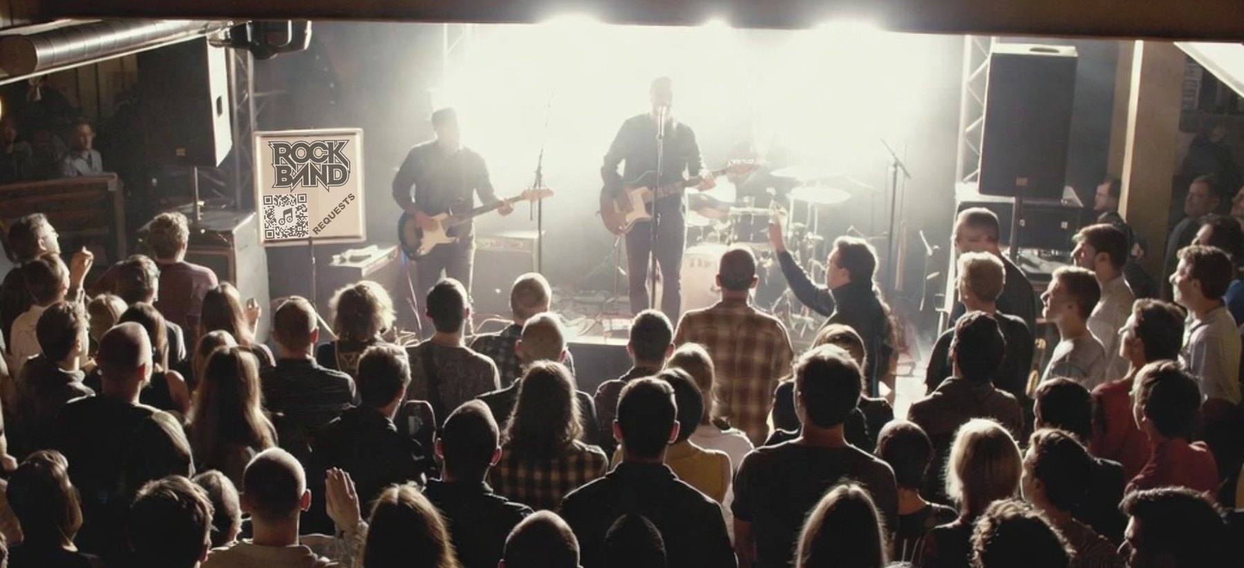 A band mid-set in a packed room, their Music Lit QR sheet propped on stage beside them